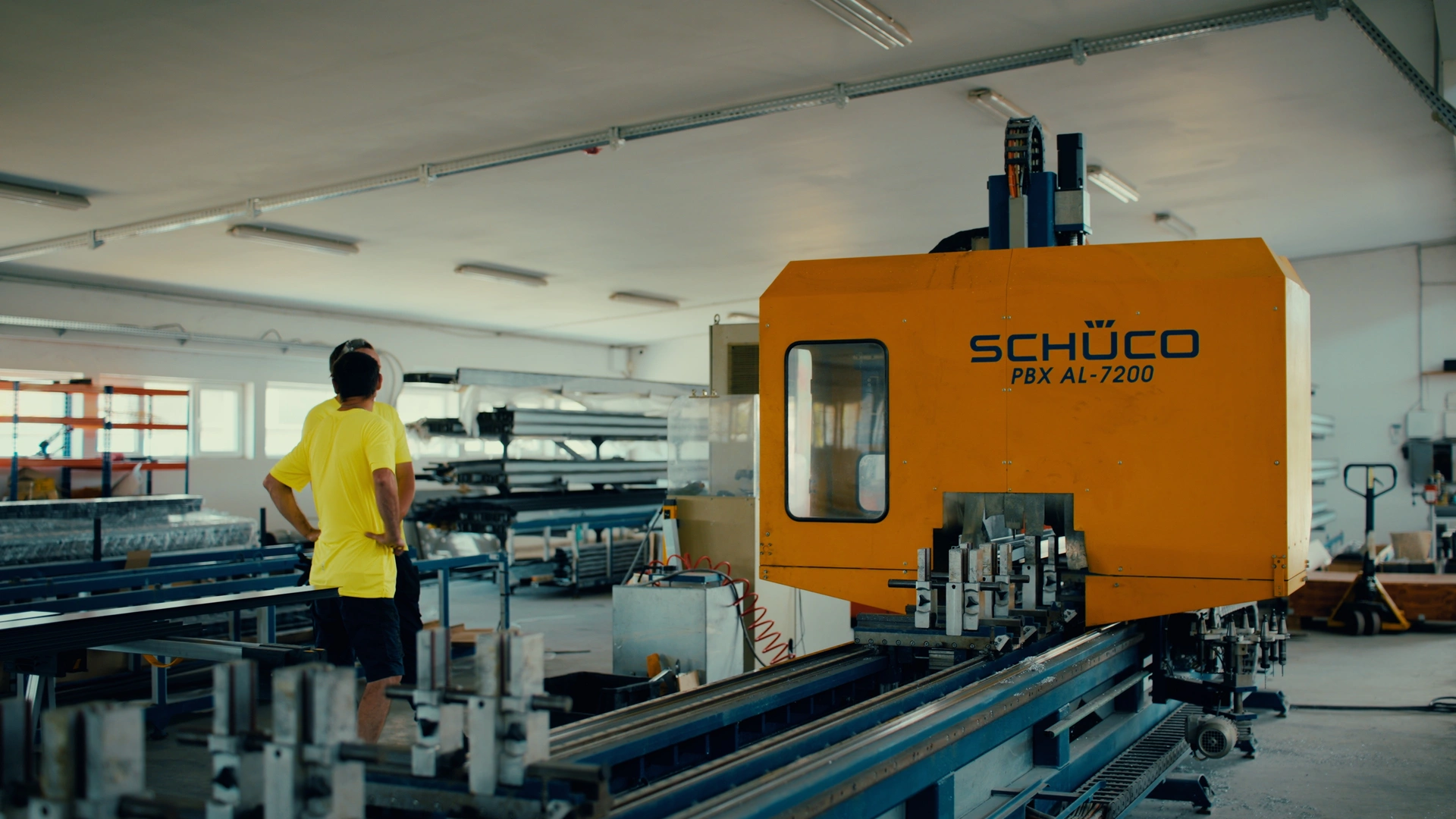 An operator beside the Schüco machining centre for aluminium window and door profiles